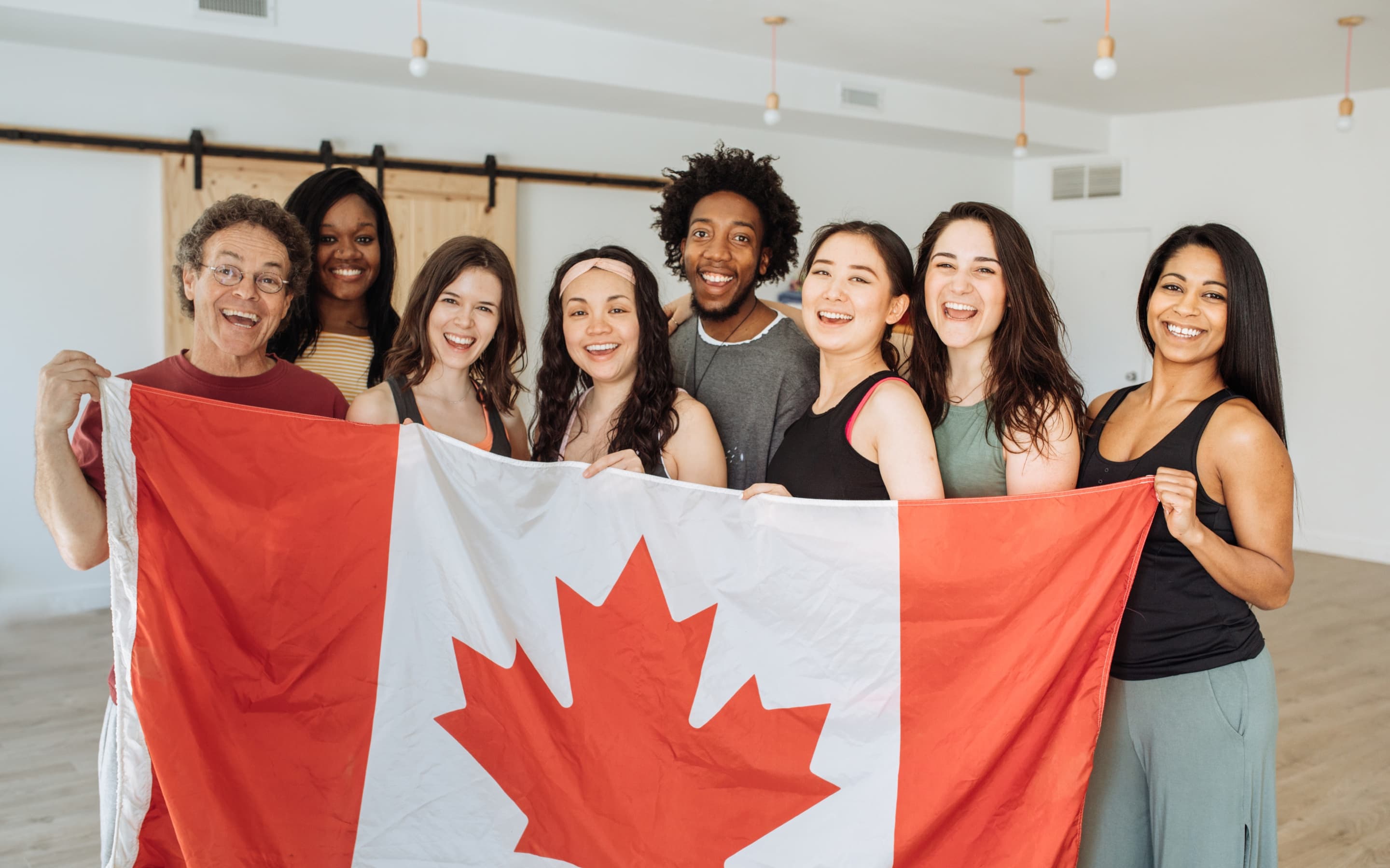 A smiling group of international students holding a Canadian flag